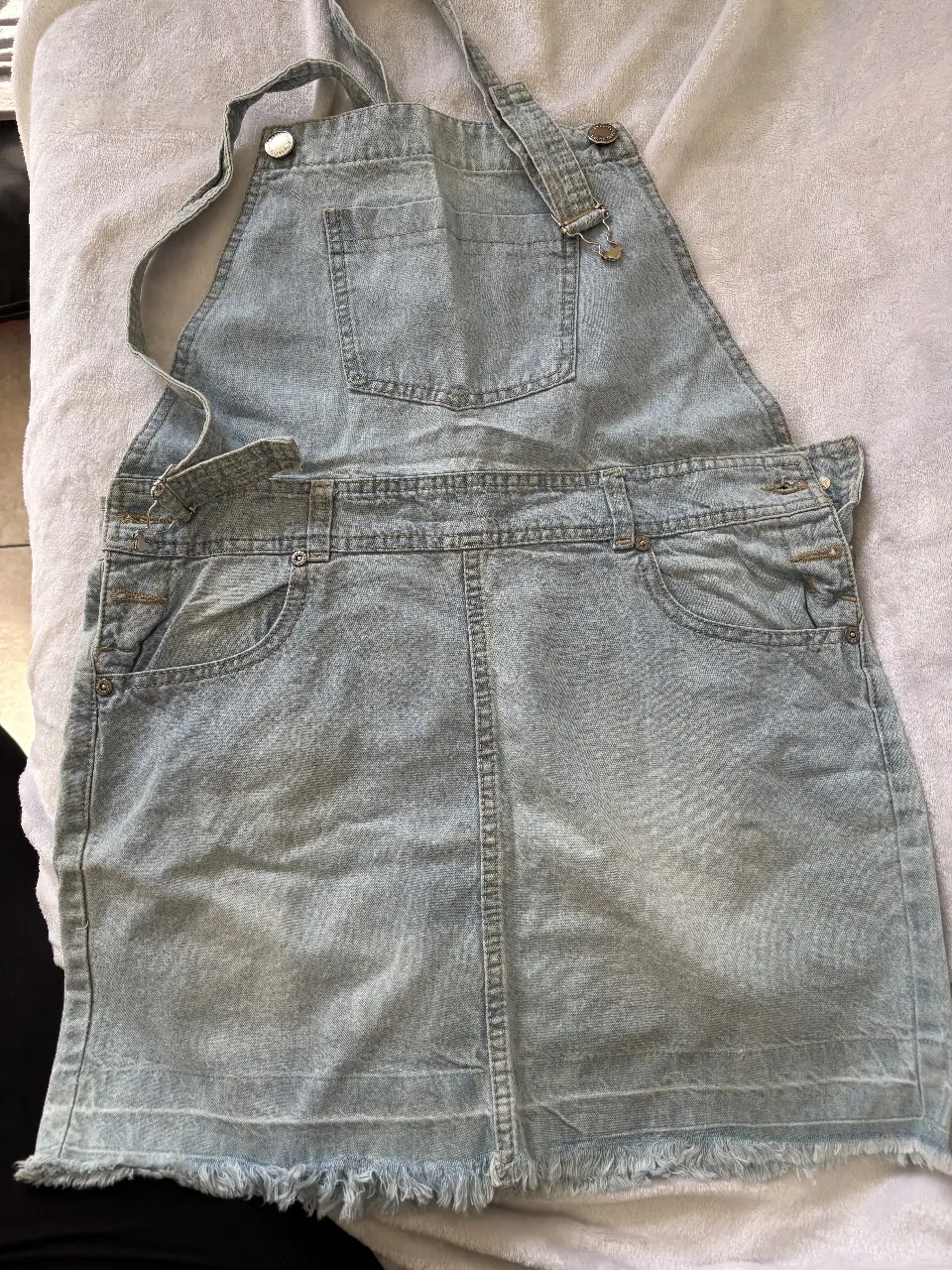 Vestido jardinero de jean, ideal para un look casual y fresco. Confeccionado en denim ligero, este vestido corto presenta un diseño clásico con tirantes ajustables y bolsillos delanteros y traseros. Perfecto para combinar con remeras, blusas o tops, este vestido es una prenda versátil y cómoda para cualquier ocasión.