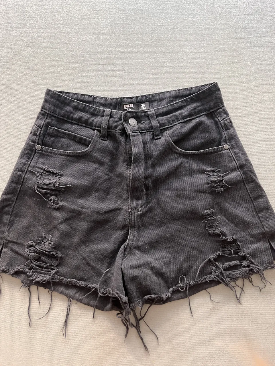 Shorts de jean negros con roturas y detalles deshilachados en los bordes. Un básico canchero para armar looks informales.