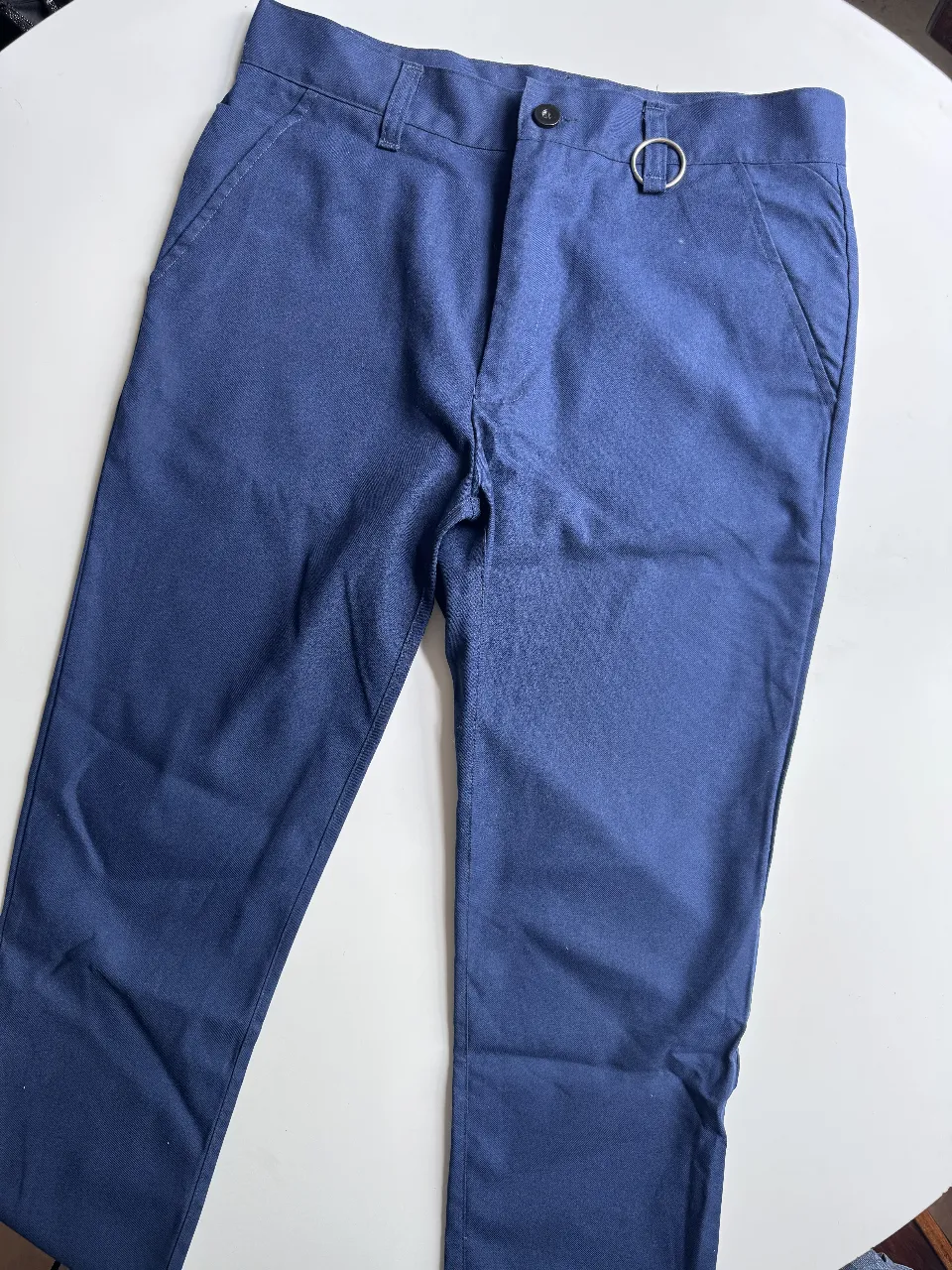Pantalón de vestir azul marino, corte recto y moderno. Detalle de aro metálico en la cintura. Ideal para un look casual o de trabajo.