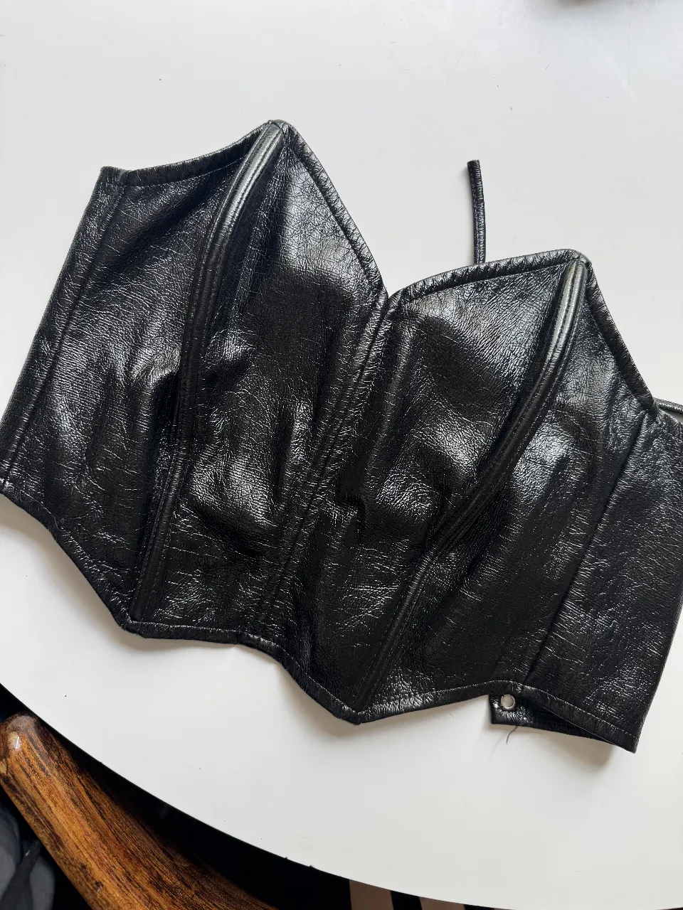 Top estilo corset de cuero sintético negro, con detalles de ojalillos y cordones para ajustar. Ideal para un look audaz y moderno.