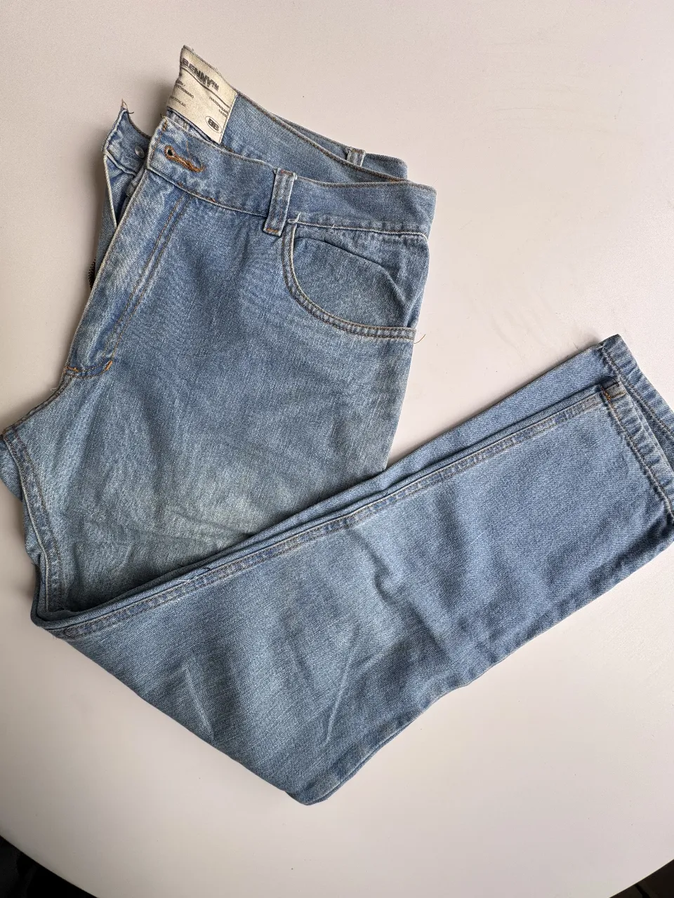 Jeans tiro alto de corte recto, con lavado celeste desgastado y detalles de costuras a la vista. Un clásico infaltable para cualquier guardarropas.