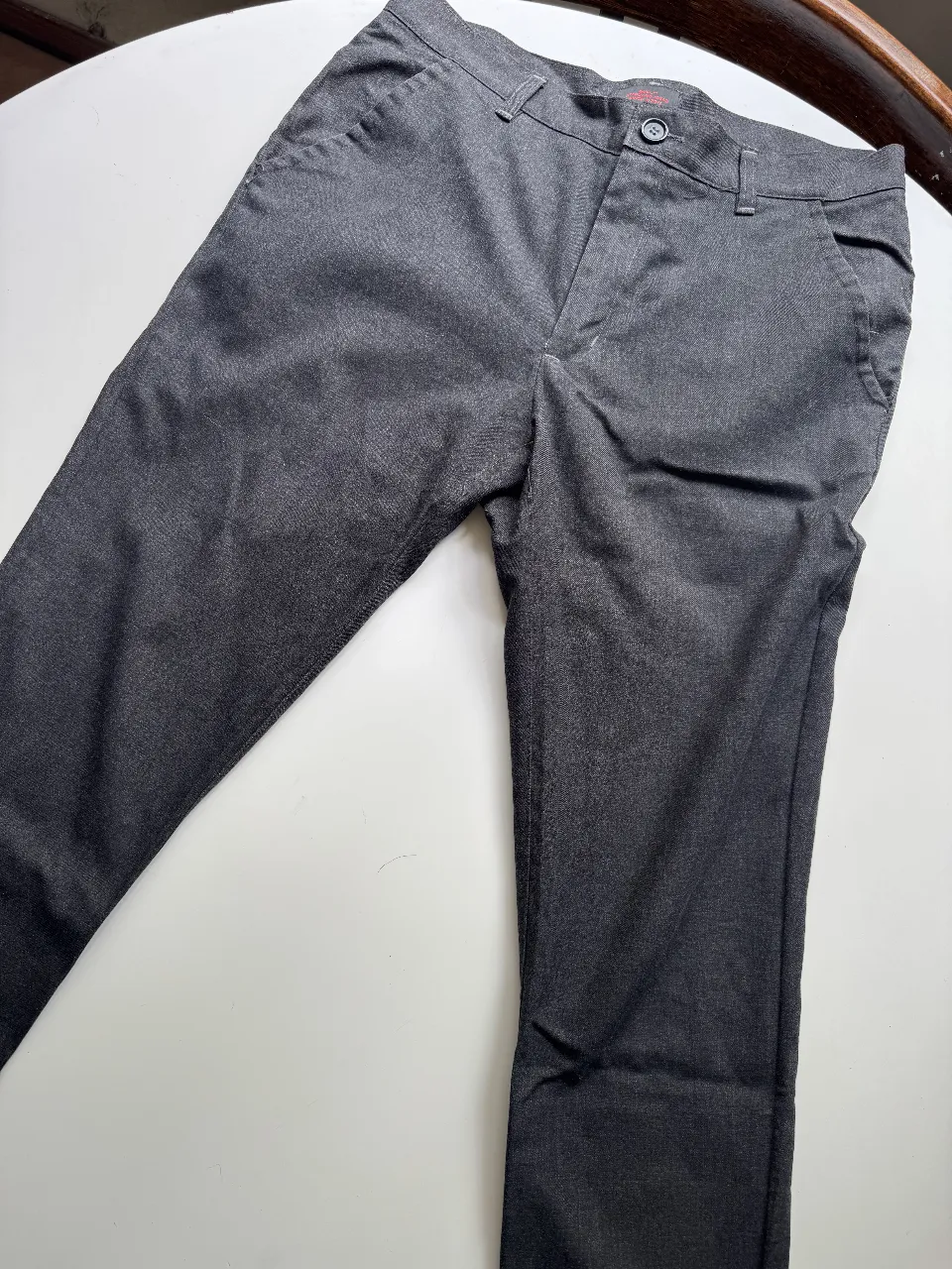 Pantalón de vestir gris oscuro, ideal para un look formal o casual elegante. Posee bolsillos frontales y un corte recto que favorece la silueta.