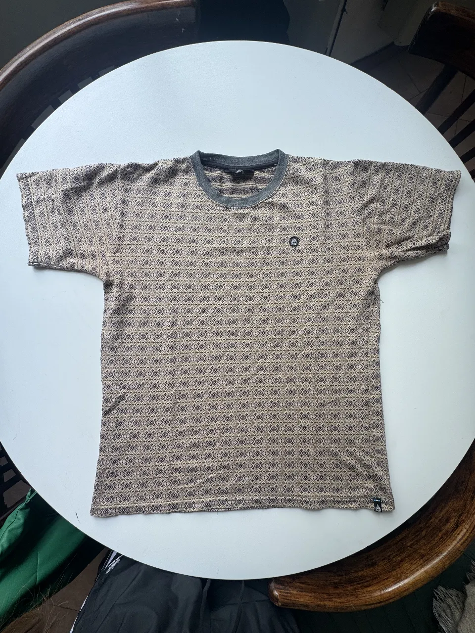 Remera estampada con un diseño geométrico en tonos tierra y gris. Cuello redondo y mangas cortas.  Marca camarón brujo, sin usar como nueva 