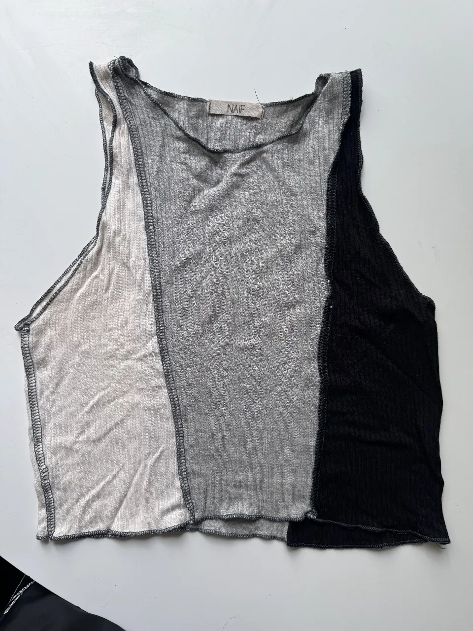 Musculosa crop de diseño moderno y original, con paneles de diferentes texturas y colores (blanco, gris y negro).