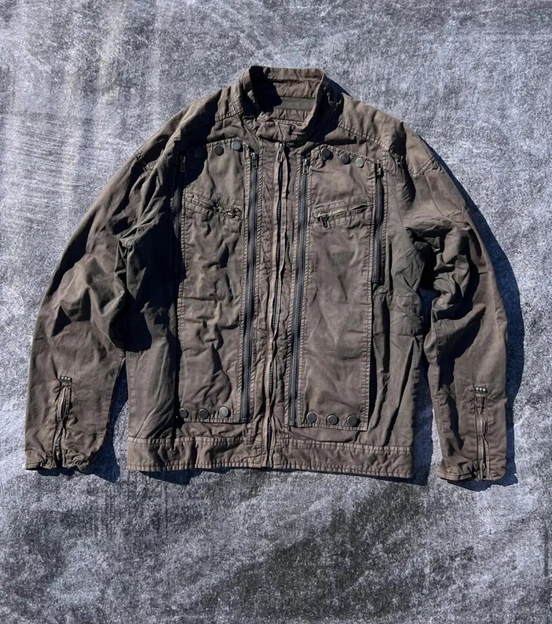 Campera bomber marrón con múltiples cierres y botones. Estilo utilitario y detalles funcionales. MEDIDAS: Talle: L - Ancho: 56cm - Largo: 67cm