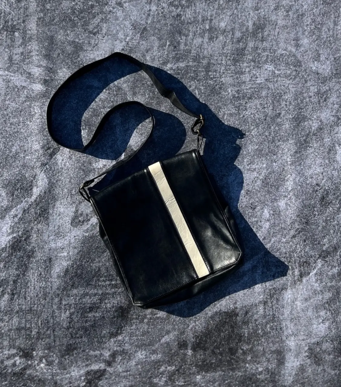 Bandolera negra con detalle blanco central de cuero. Ideal para llevar la notebook con estilo. Perfecta para un look casual y moderno.