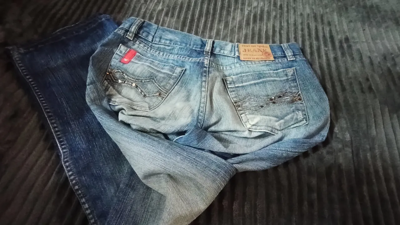 Jeans de corte clásico con detalles desgastados y bordados en los bolsillos traseros. Presentan un lavado claro con zonas más claras en las piernas.