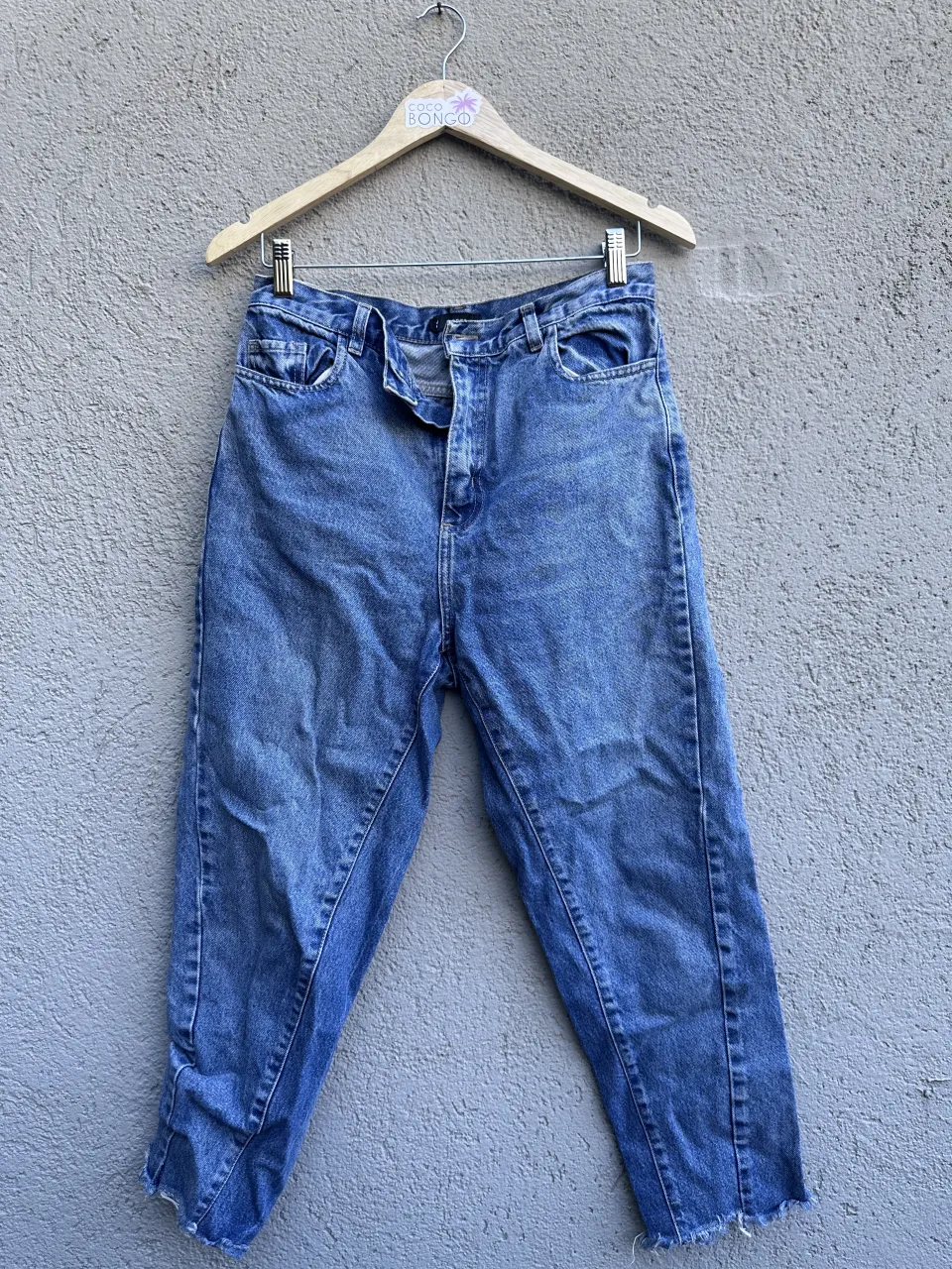 Jean de tiro alto, color azul, con roturas en los bajos.