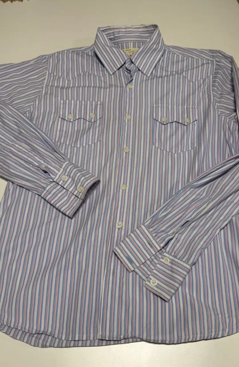 Camisa a rayas celeste y rosa de la marca Old Bridge, con dos bolsillos en el pecho y botones blancos. Ideal para un look casual y fresco. Largo: 69 cm. Sisa: 52 cm (contorno 104 cm)