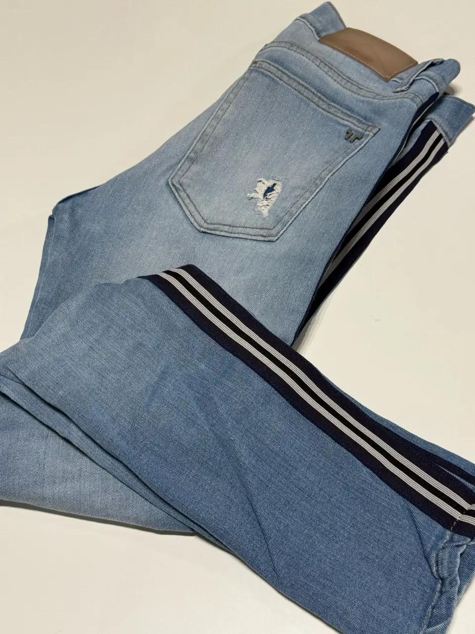 Jeans de hombre elastizado Tascani celeste con roturas y detalles de rayas en los laterales. Talle 28. Están en buen estado pero por el uso las roturas de las rodillas son bastante grandes. Cintura: 74 cm. Largo 91 cm.