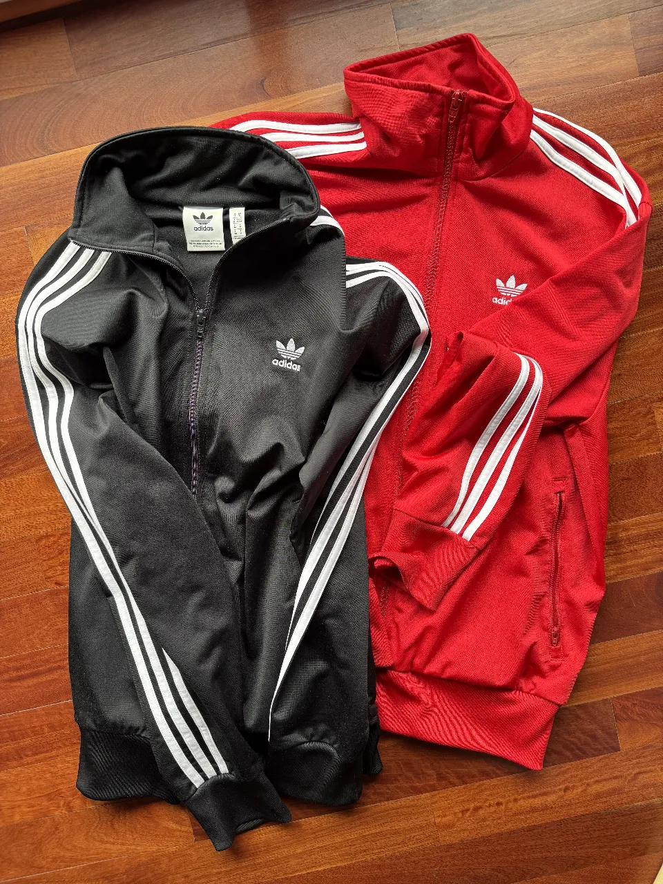 Camperas Adidas Originals Firebird. Ambas talle M, negro y rojo,  con las clásicas tres tiras blancas en las mangas. Precio por unidad.
