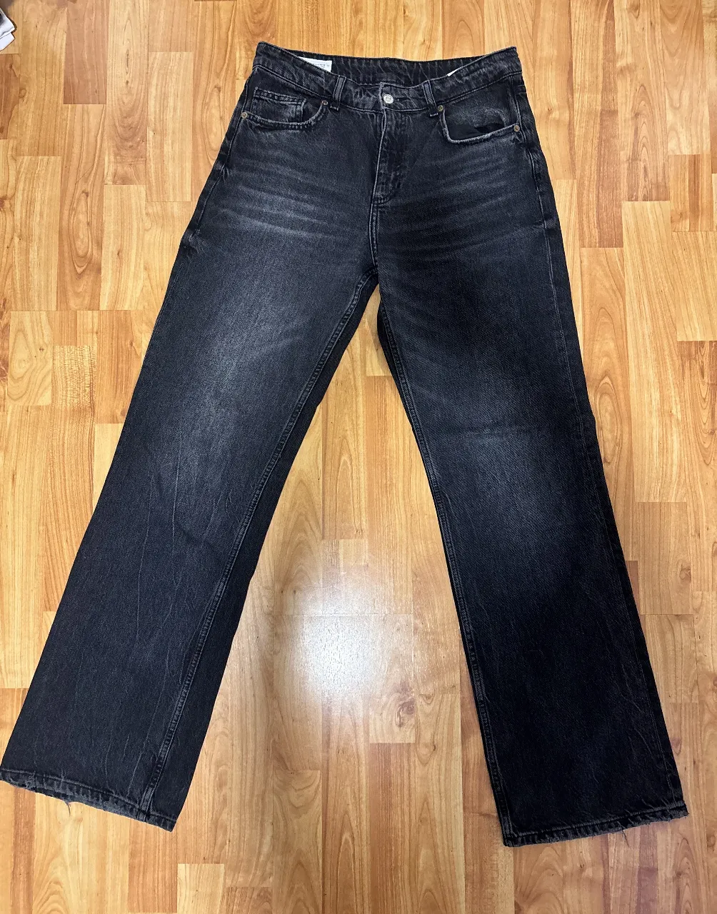 Jeans negros tiro alto, corte recto y pierna ancha. Lavado desgastado con detalles sutiles de roturas. Ideales para un look casual y moderno.