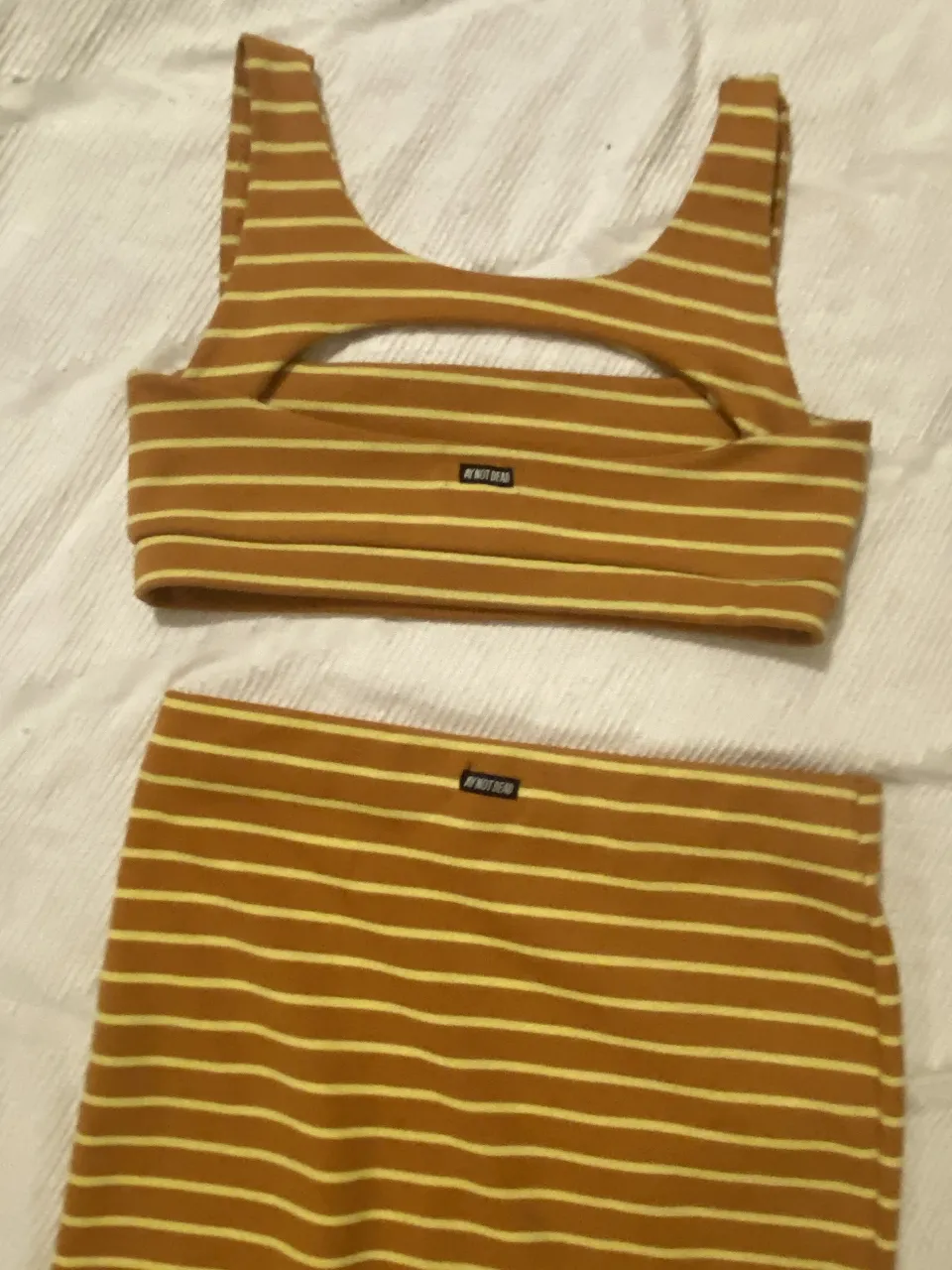 Conjunto de top y pollera a rayas. El top es de corte deportivo con un recorte en el frente. La pollera es recta y de largo hasta la rodilla. Ideal para un look casual y canchero.