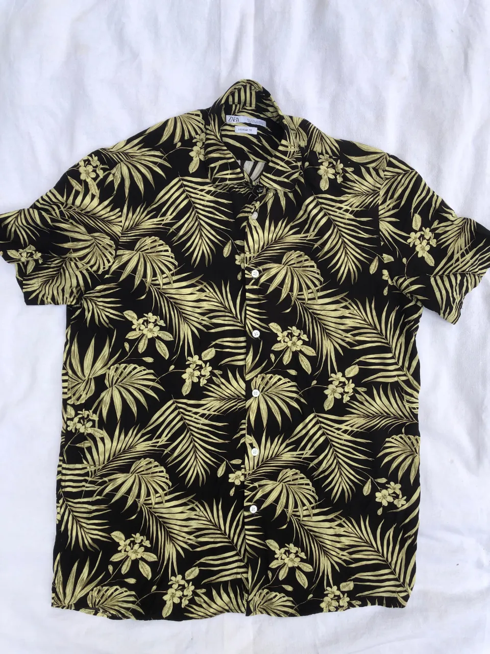 Camisa estampada con hojas tropicales en negro y amarillo. Posee cuello clásico y botones al frente.
Medidas:
hombros 47cm
axilas 57cm