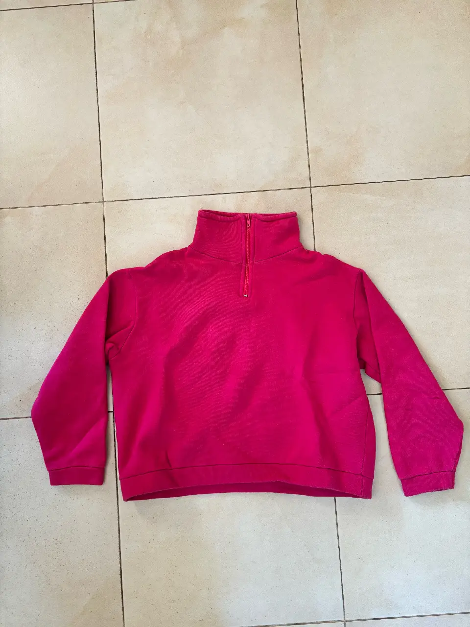 Buzo con cierre y cuello alto en color rosa. Ideal para un look casual y abrigado.