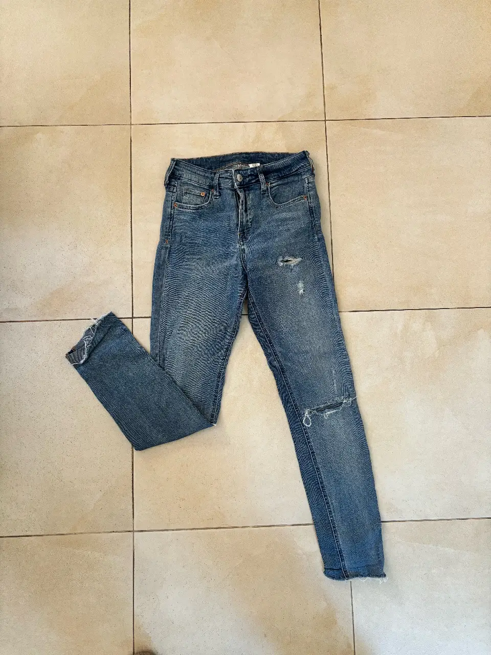 Jeans tiro alto, con roturas en la rodilla. Corte recto, ideal para un look casual y moderno.