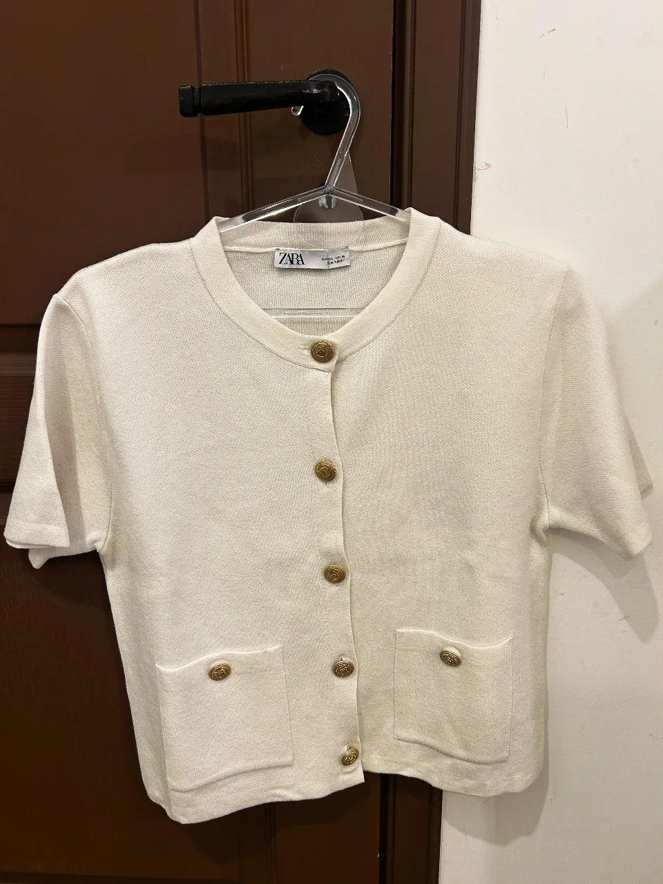 Cardigan blanco de tejido liviano con botones dorados y bolsillos frontales. Un básico canchero para elevar cualquier look.