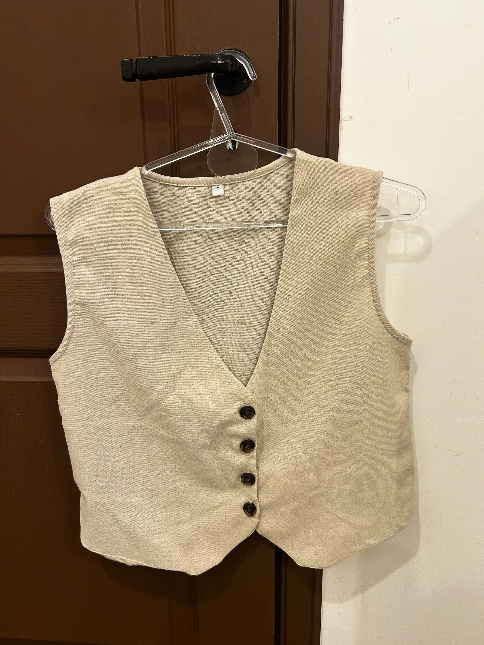 Chaleco de vestir color beige, ideal para complementar looks formales o casuales. Posee botones al frente y un corte clásico que lo hace muy versátil.