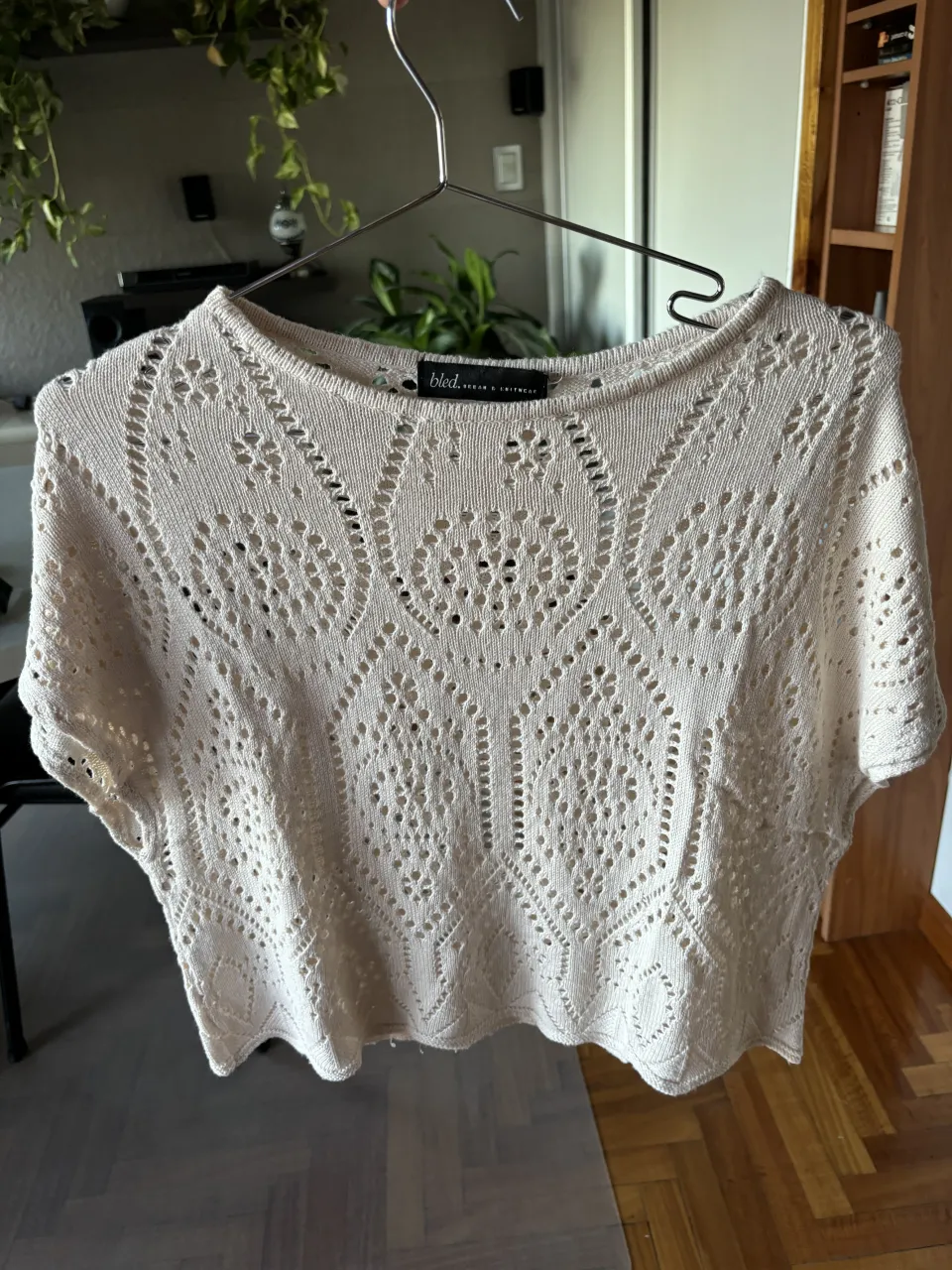 Remera de tejido de punto beige/arena con detalles calados y mangas cortas.