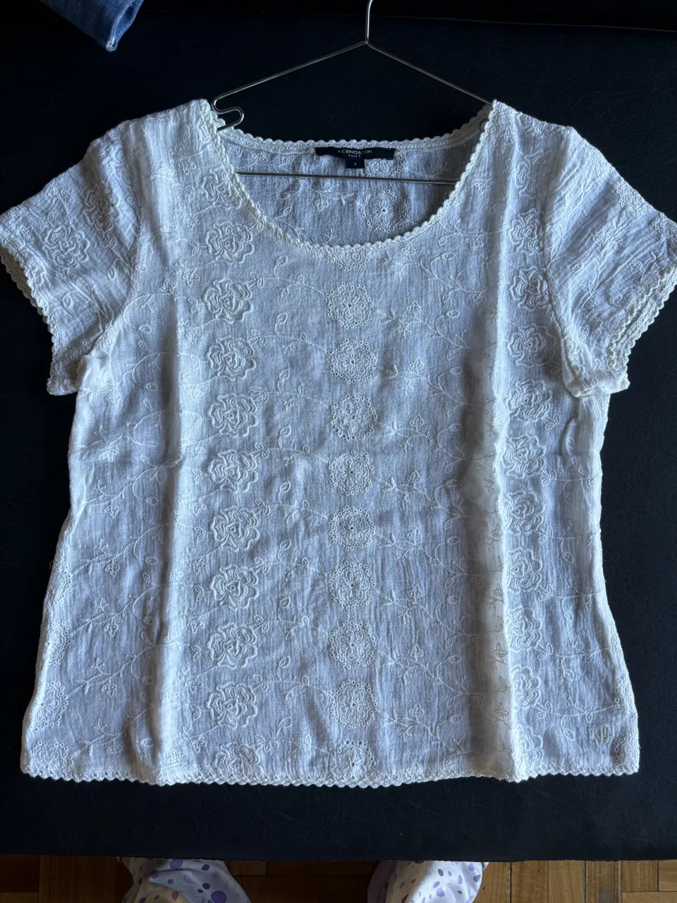 Blusa color crudo con bordado floral en relieve y detalles de puntilla en cuello y mangas.