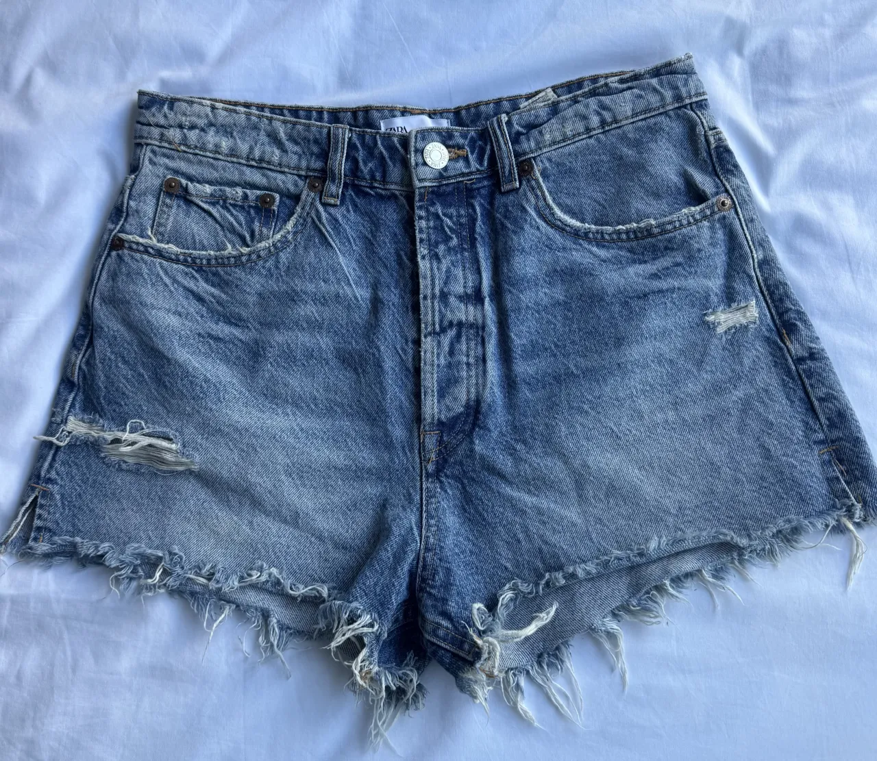 Shorts de jean tiro alto con roturas y detalles deshilachados en los bordes.