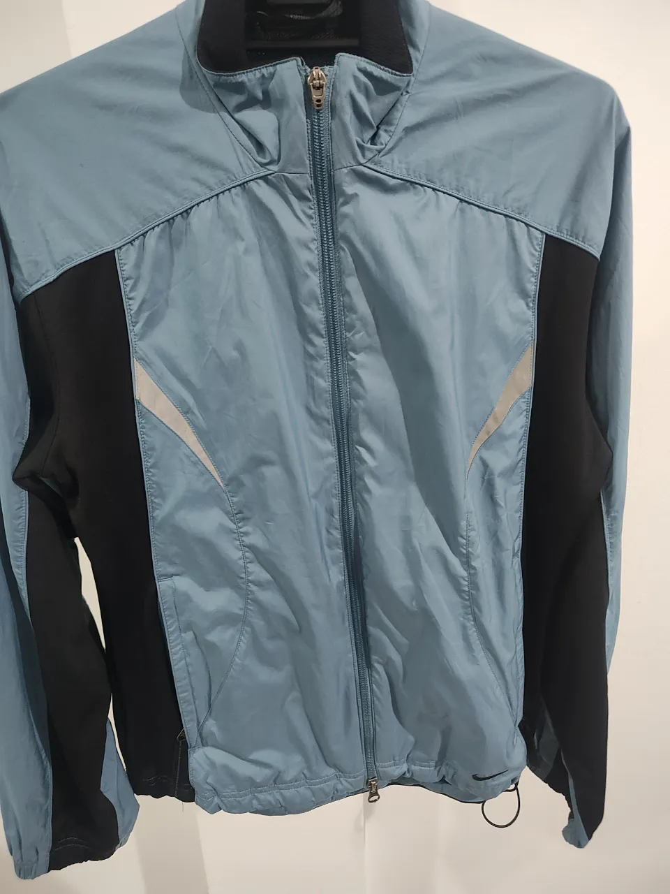 Campera deportiva Nike, ideal para running o entrenamientos. Diseño moderno en tonos celestes y negro, con detalles reflectantes. Perfecta para mantenerte cómodo y con estilo mientras te ejercitás. El único detalle que tiene es que le falta la lengüeta del cierre. Pero este funciona perfectamente.no se nota 