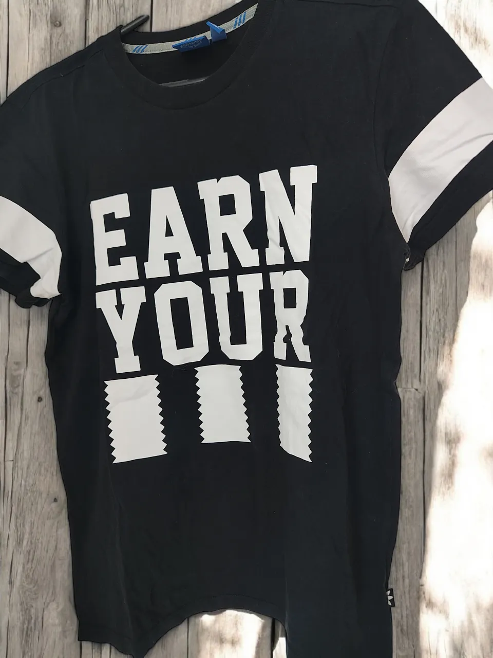 Remera negra de manga corta con estampa blanca "EARN YOUR". Ideal para un look casual y deportivo.