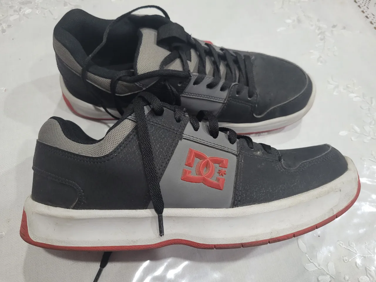 Zapatillas DC Shoes de hombre, negras con detalles en gris y rojo. Ideales para uso diario y estilo urbano.