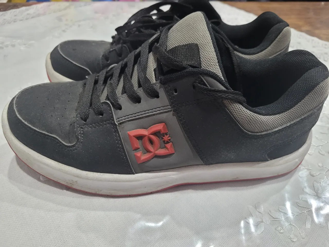 Zapatillas DC Shoes negras con detalles en rojo, ideales para un look skater o casual. Diseño moderno y resistente.