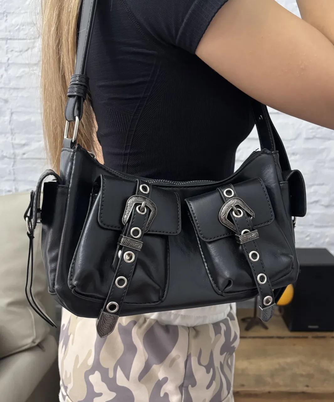 Cartera negra estilo Y2K con múltiples bolsillos y detalles de hebillas plateadas.
