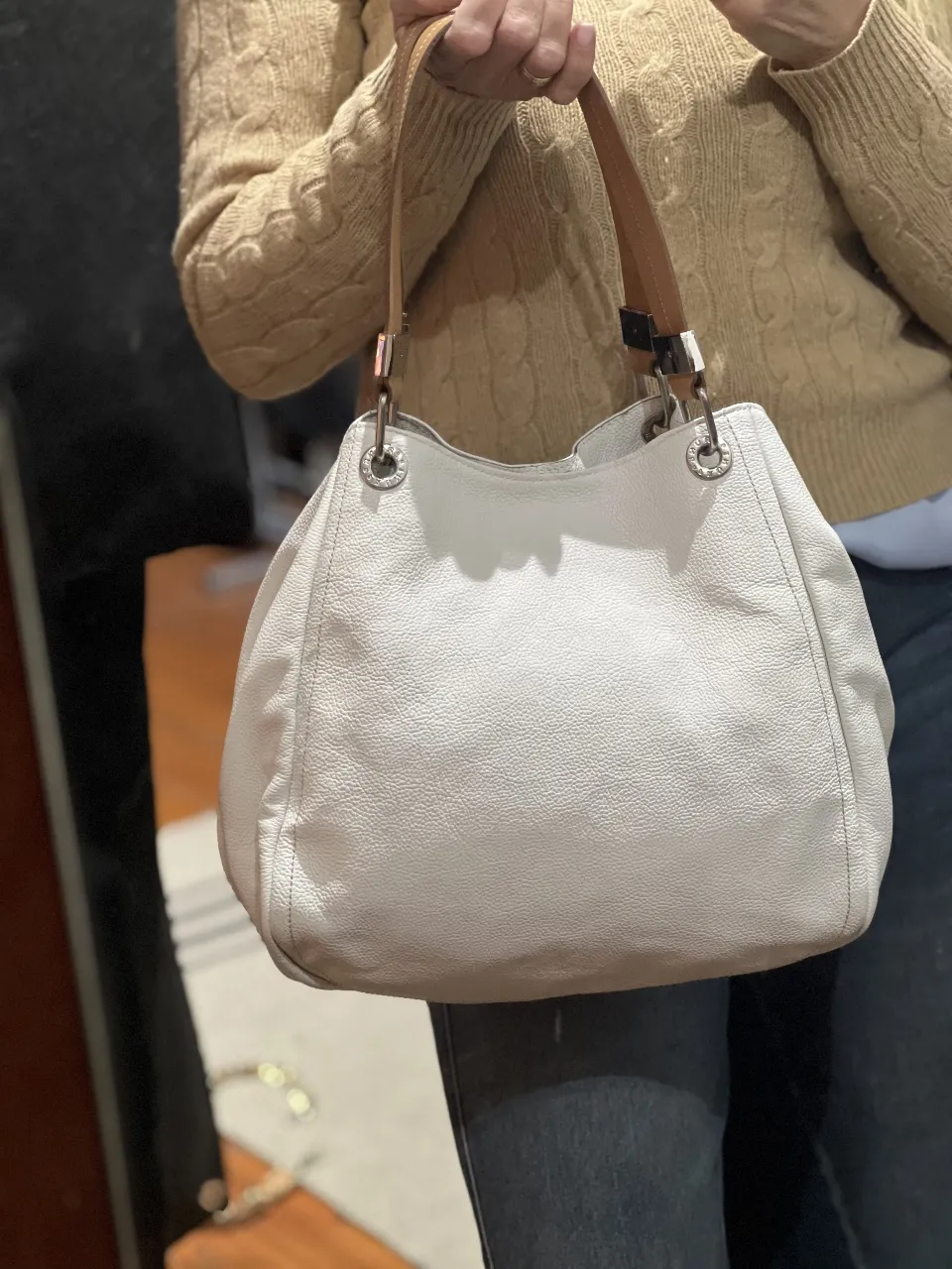 Cartera Prune de cuero blanco con detalles marrones y herrajes plateados. Diseño elegante y espacioso, ideal para uso diario.
