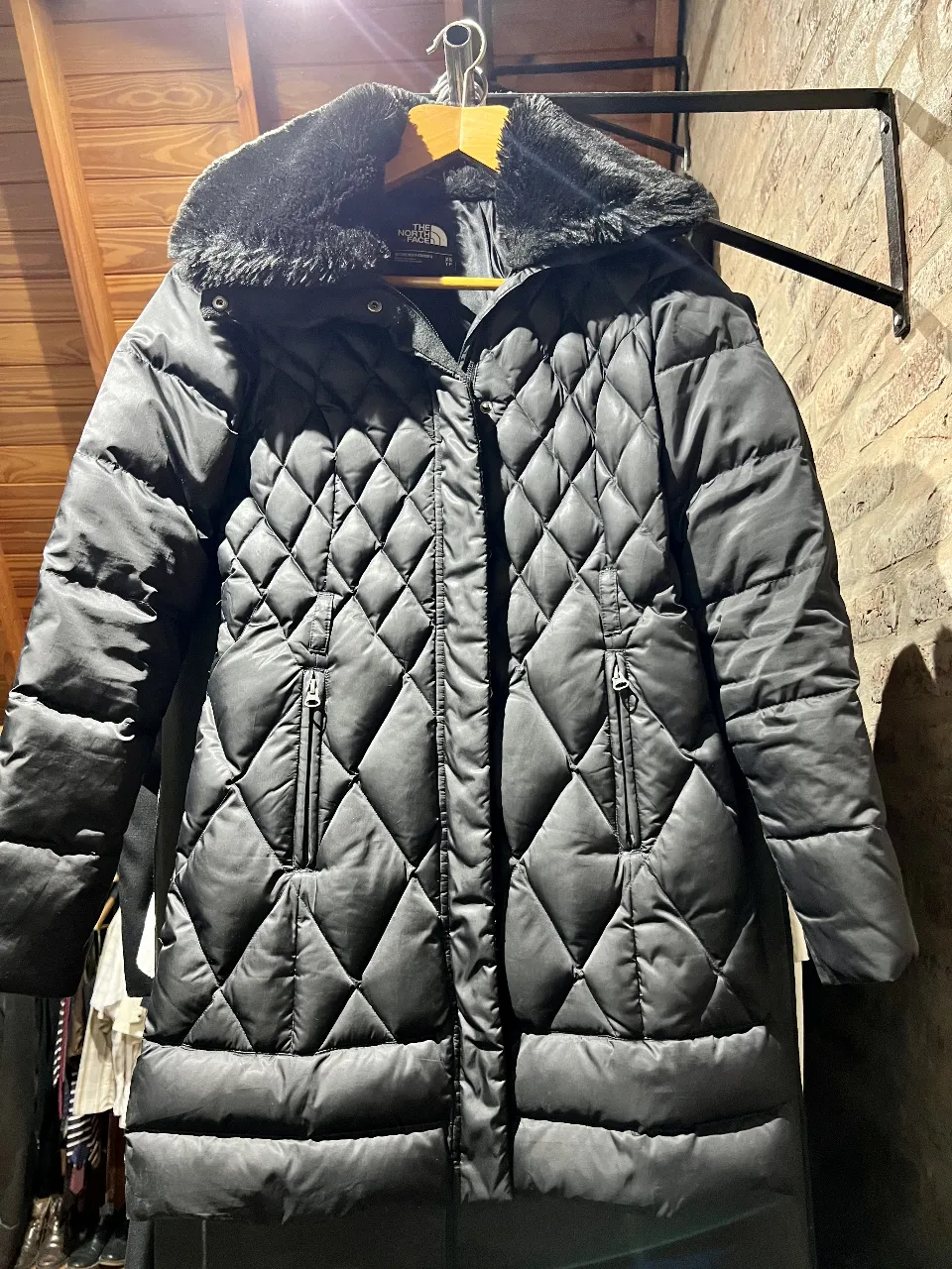 Campera larguita de pluma The North Face para mujer, color negro, talle XS. Diseño acolchado  y detalles de piel sintética en el cuello (desmontable). con capucha  escondida. Ideal para el invierno. Plumas: 600Pro