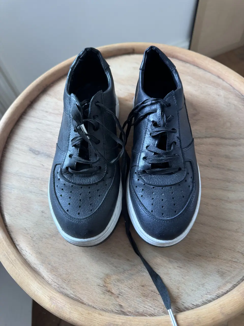 Zapatillas negras de cuero con suela blanca. Diseño clásico y versátil, ideales para un look casual y moderno.