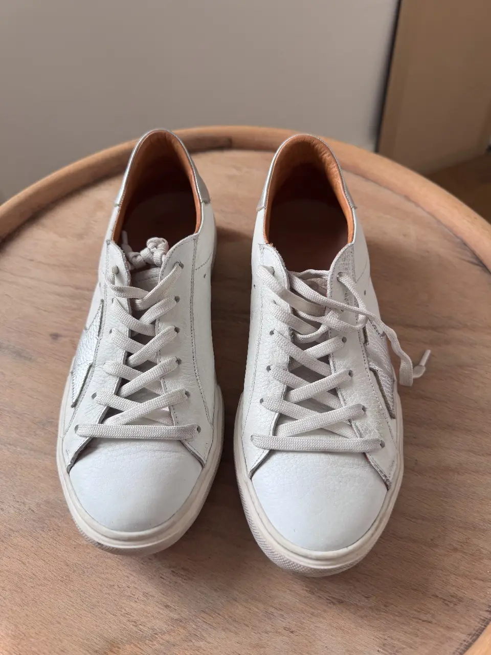 Zapatillas blancas de cuero con detalles plateados y estrella en el lateral. Ideales para un look casual y cómodo.