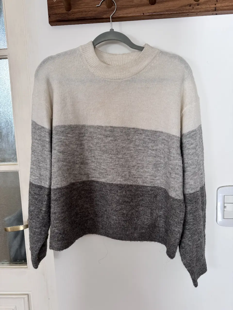 Sweater de cuello redondo con diseño a rayas horizontales en tonos grises y blanco. Ideal para un look casual y abrigado.