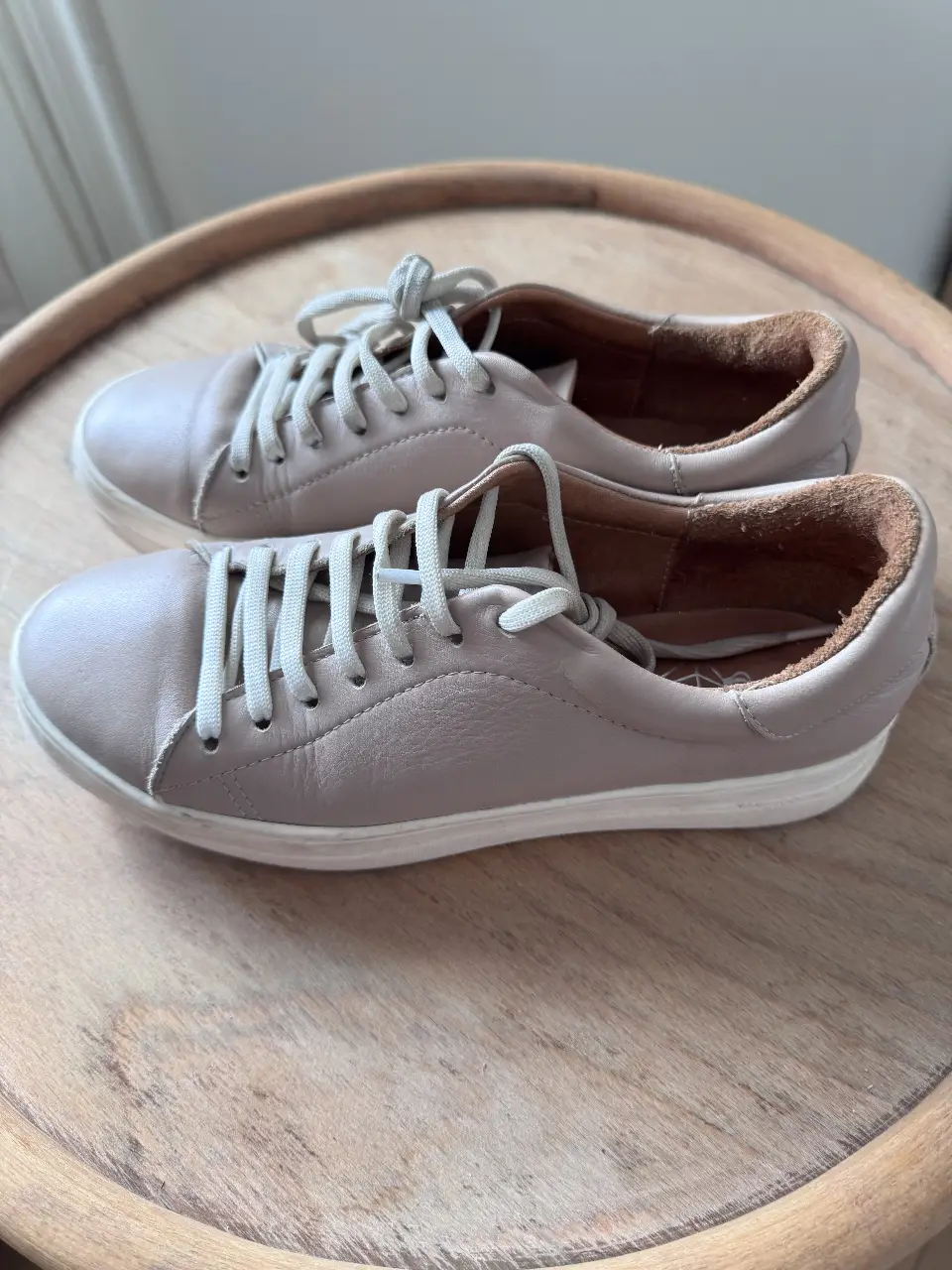 Zapatillas de cuero color gris claro con cordones blancos. Ideales para un look casual y cómodo.