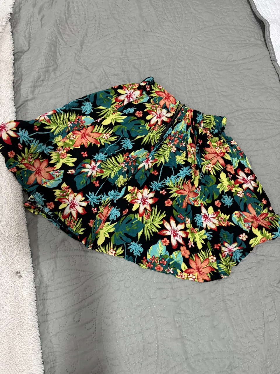 Pollera de tela con estampa floral de flores y hojas en colores vibrantes sobre fondo negro. Cintura elastizada.