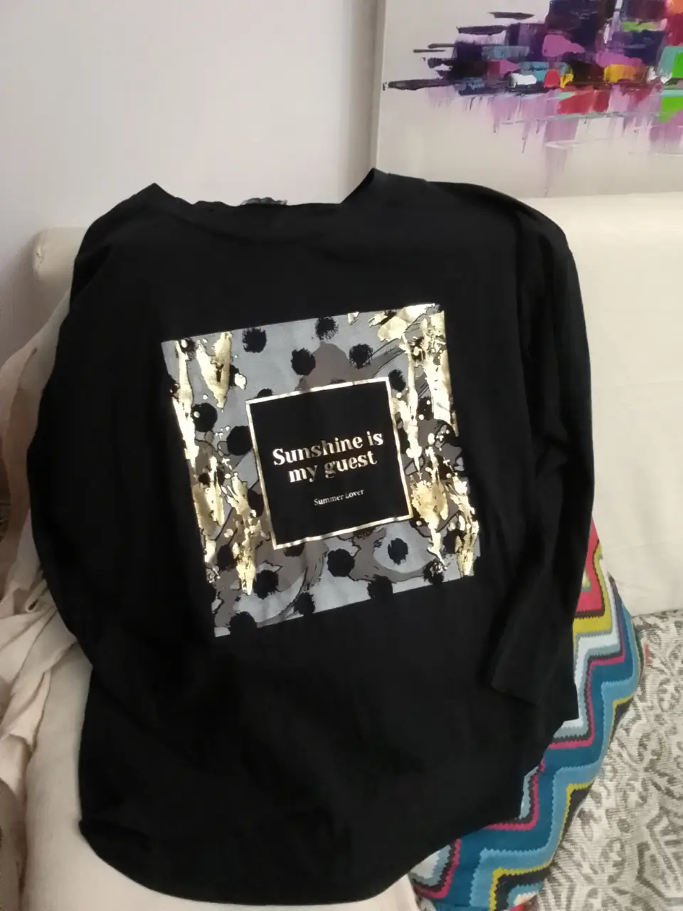 Remera negra de manga larga con estampado "Sunshine is my guest" en dorado y gris. Ideal para un look casual y moderno.