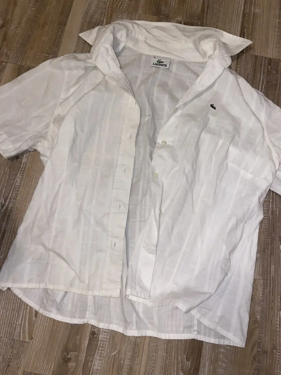 Camisa de mujer Lacoste blanca a rayas, manga corta, ideal para un look casual y fresco.