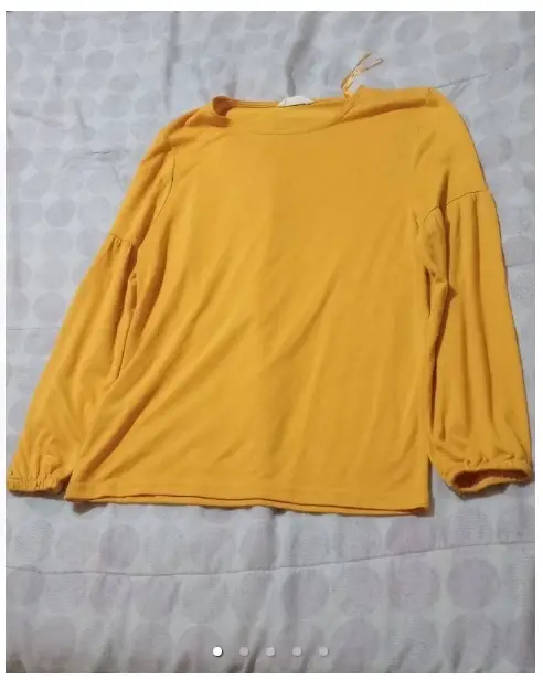 Blusa amarilla de manga larga con puños elastizados. Cuello redondo y detalle de cinta. Talle XS.