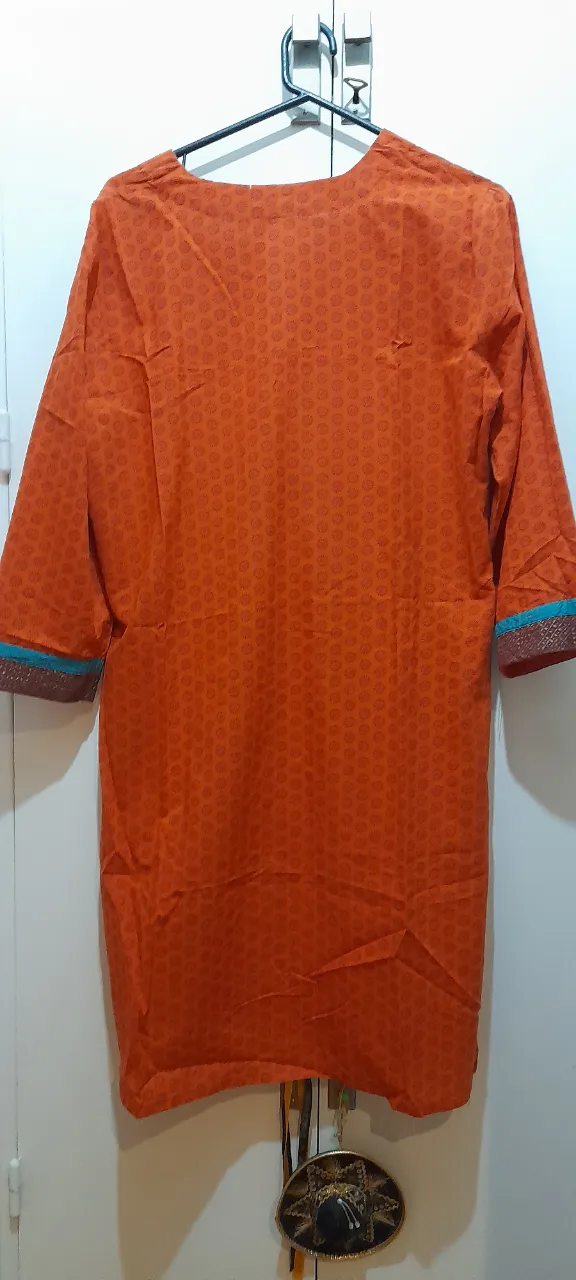 Vestido hindu, naranja estampada con detalles en cuello y mangas.Con bolsillos. Ideal para un look casual y cómodo.