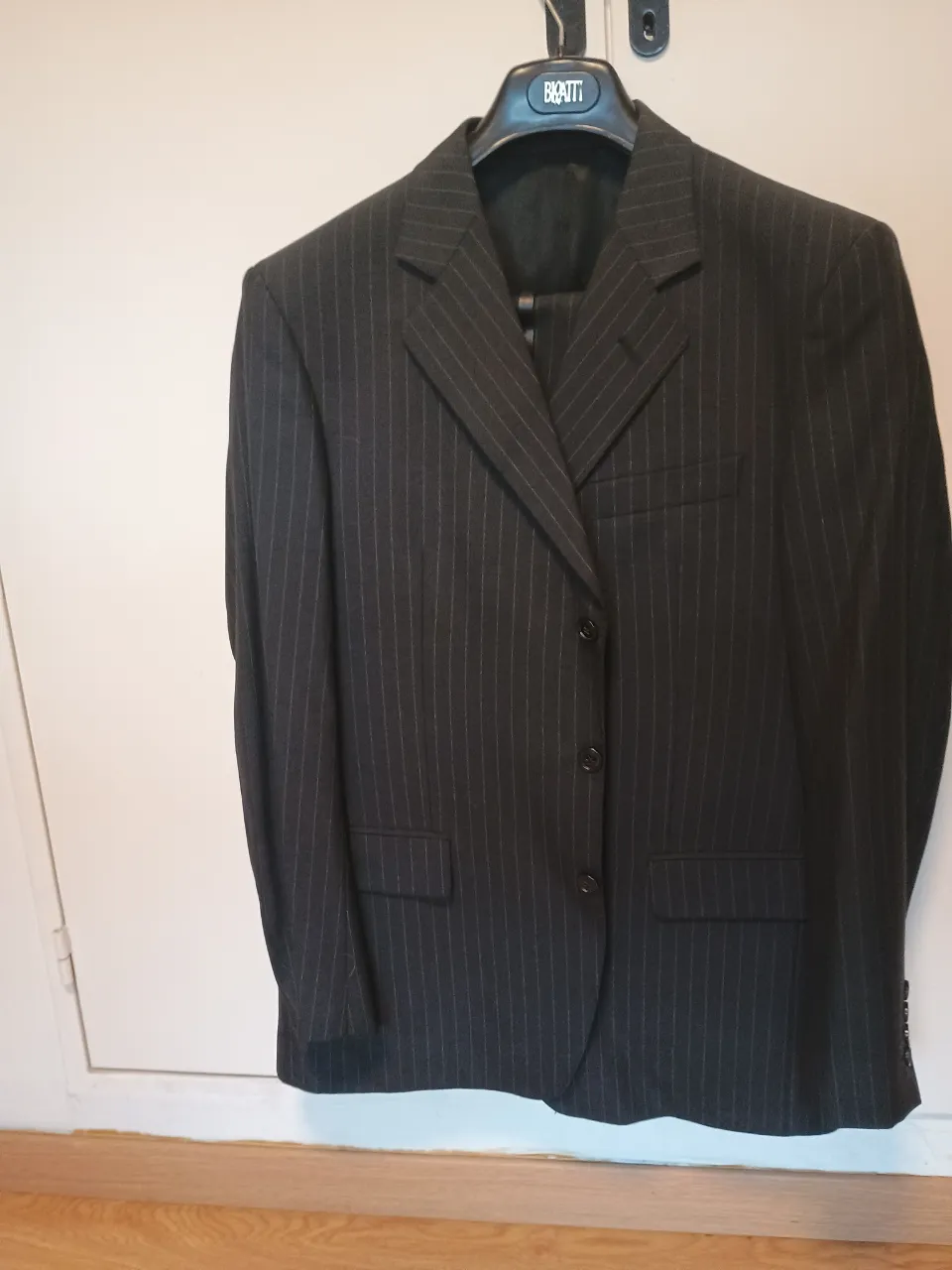 Traje de hombre gris oscuro a rayas, ideal para eventos formales y trabajo. Blazer con botones y solapas clásicas, pantalón a juego.