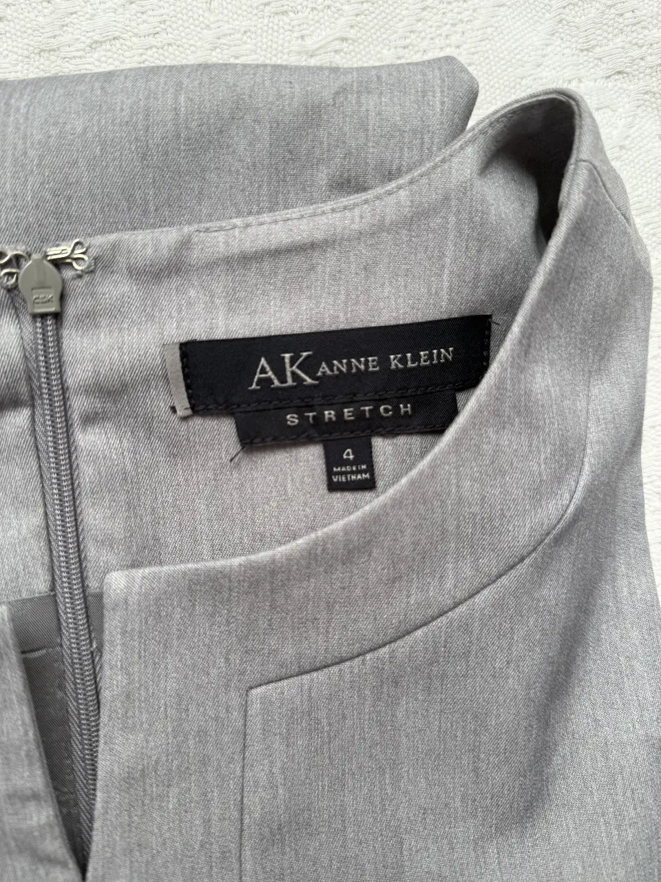 Vestido midi gris de la marca Anne Klein, ideal para el trabajo. Confeccionado en tela stretch, sin mangas y con cierre en la espalda.