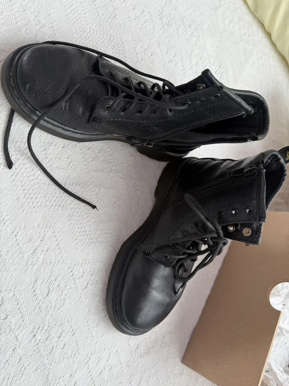 Botines Dr. Martens negros, con cierre lateral y cordones. Ideales para un look urbano y moderno.