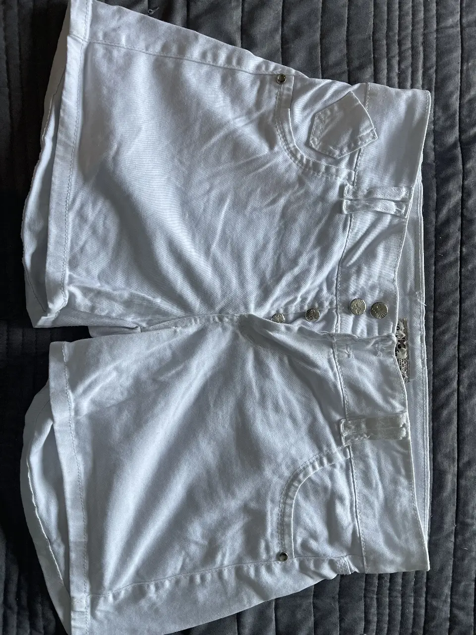 Short de jean blanco, tiro medio, con detalles de botones y bolsillos. Ideal para un look casual y fresco.