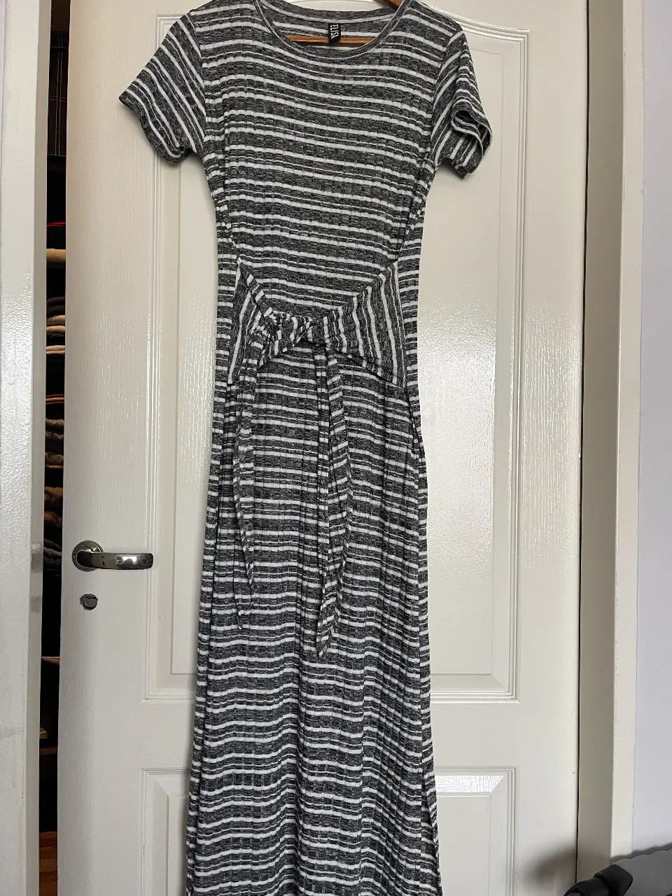 Vestido midi a rayas horizontales en gris y blanco, con mangas cortas y detalle de lazo en la cintura. Ideal para un look casual y cómodo.