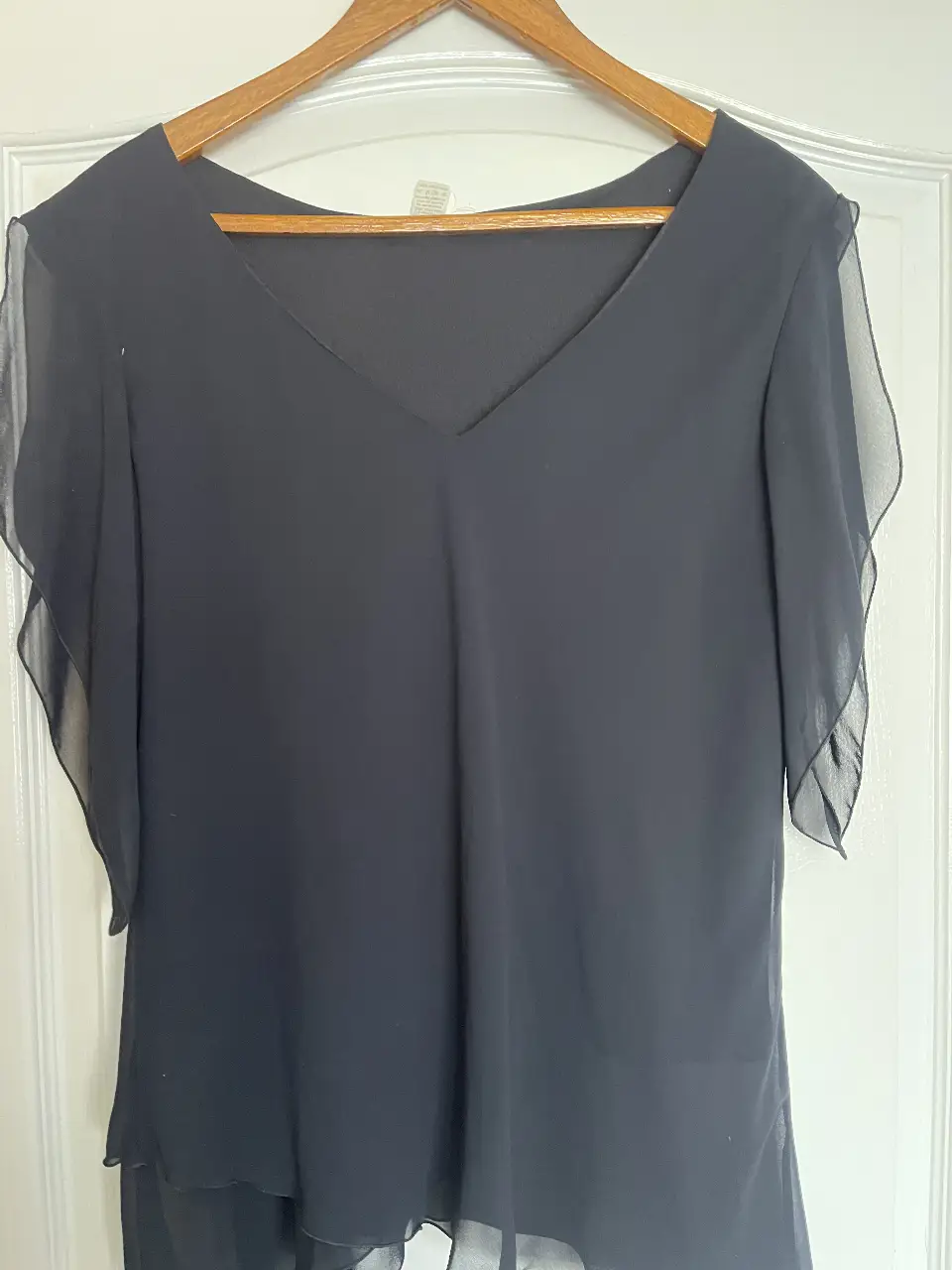 Blusa negra con mangas cortas estilo mariposa, ideal para eventos formales o salidas nocturnas. Confeccionada en un tejido ligero y fluido, ofrece un ajuste cómodo y elegante.