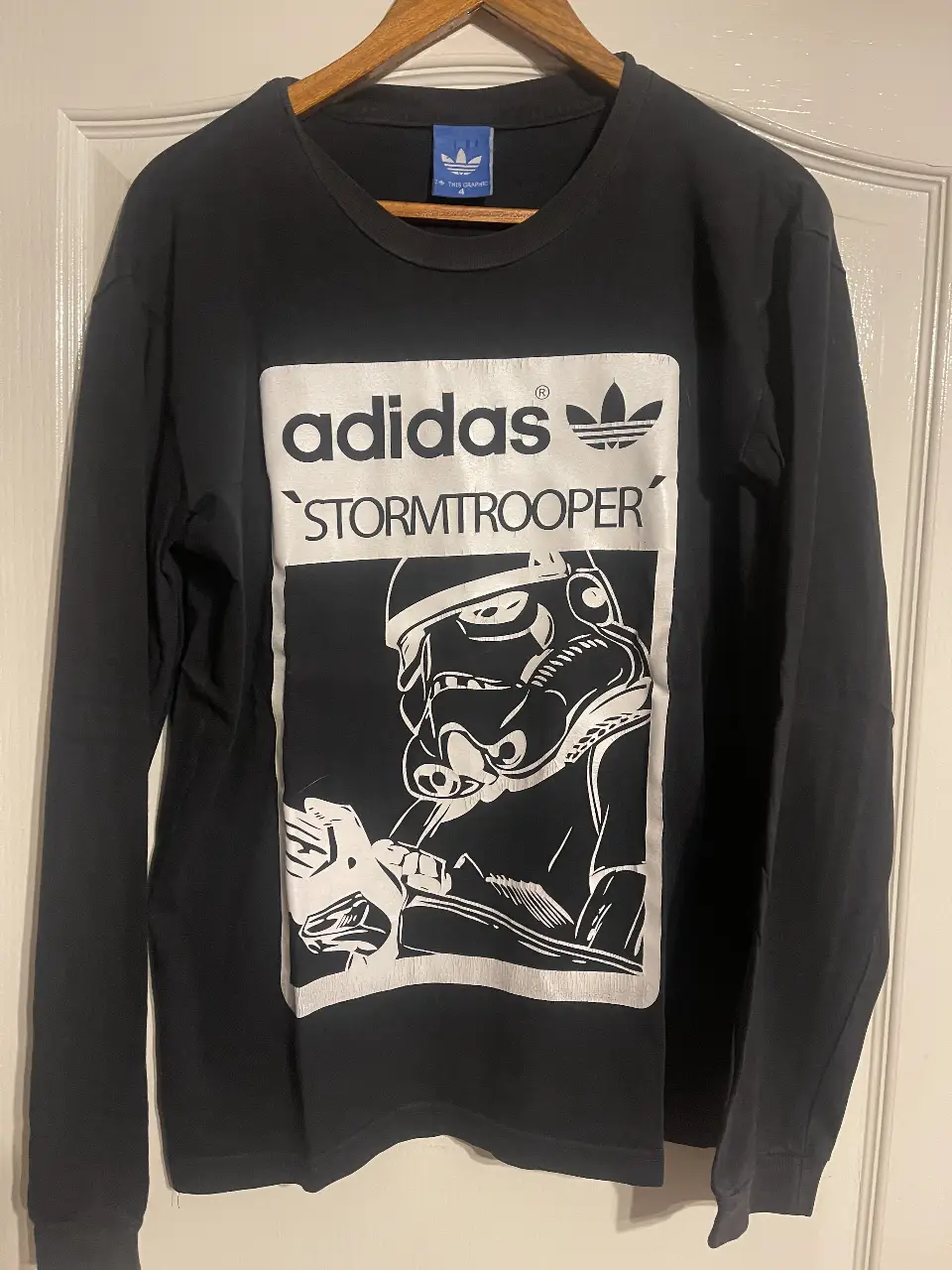 Remera manga larga Adidas x Star Wars Stormtrooper. Estampado grande del personaje en blanco sobre fondo negro. Cuello redondo. Ideal para un look casual y urbano.