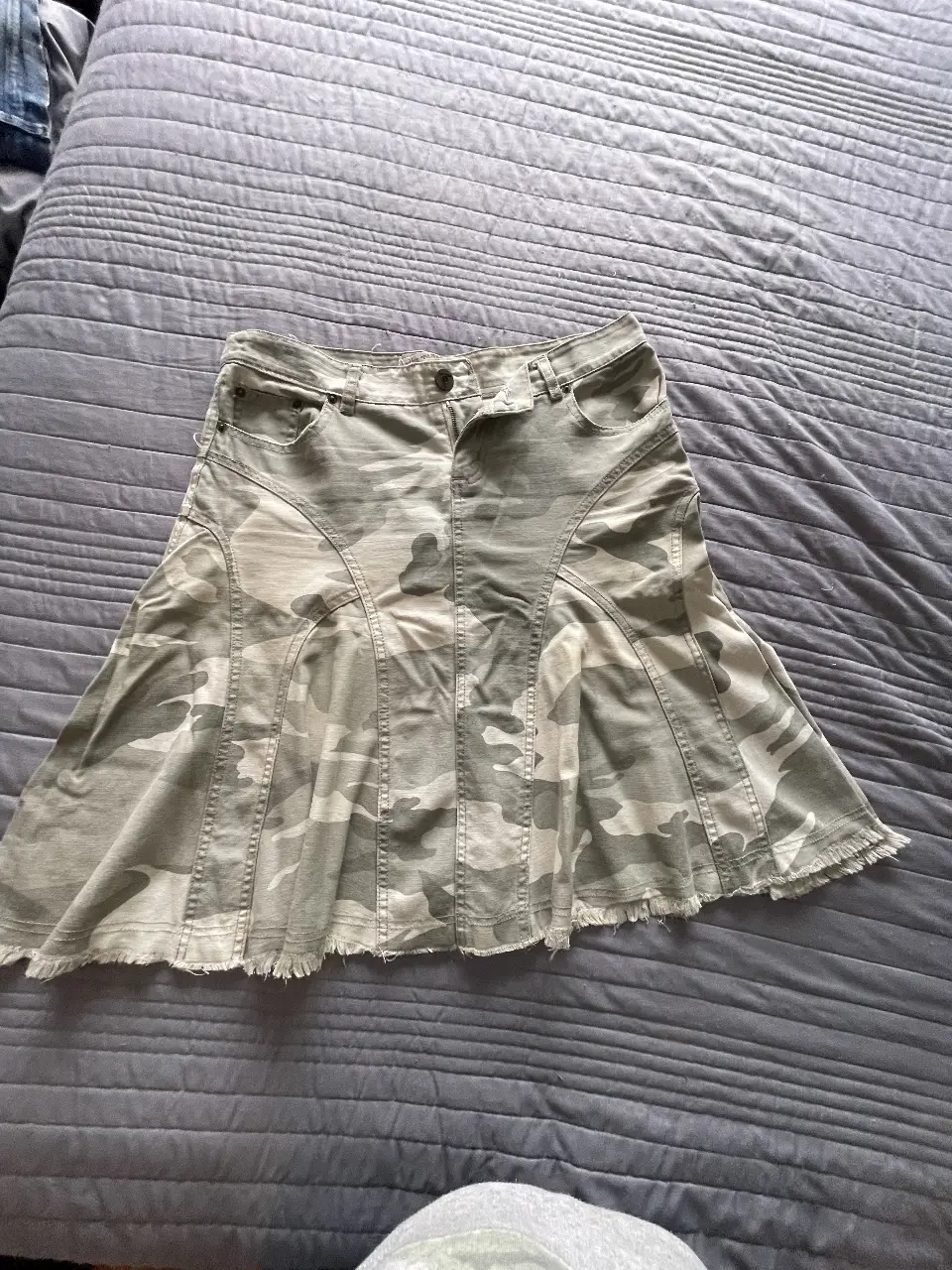 Pollera de jean con estampado camuflado. Corte evasé con detalles de costura y flecos en el borde inferior. Talle M de la marca Tabatha.
