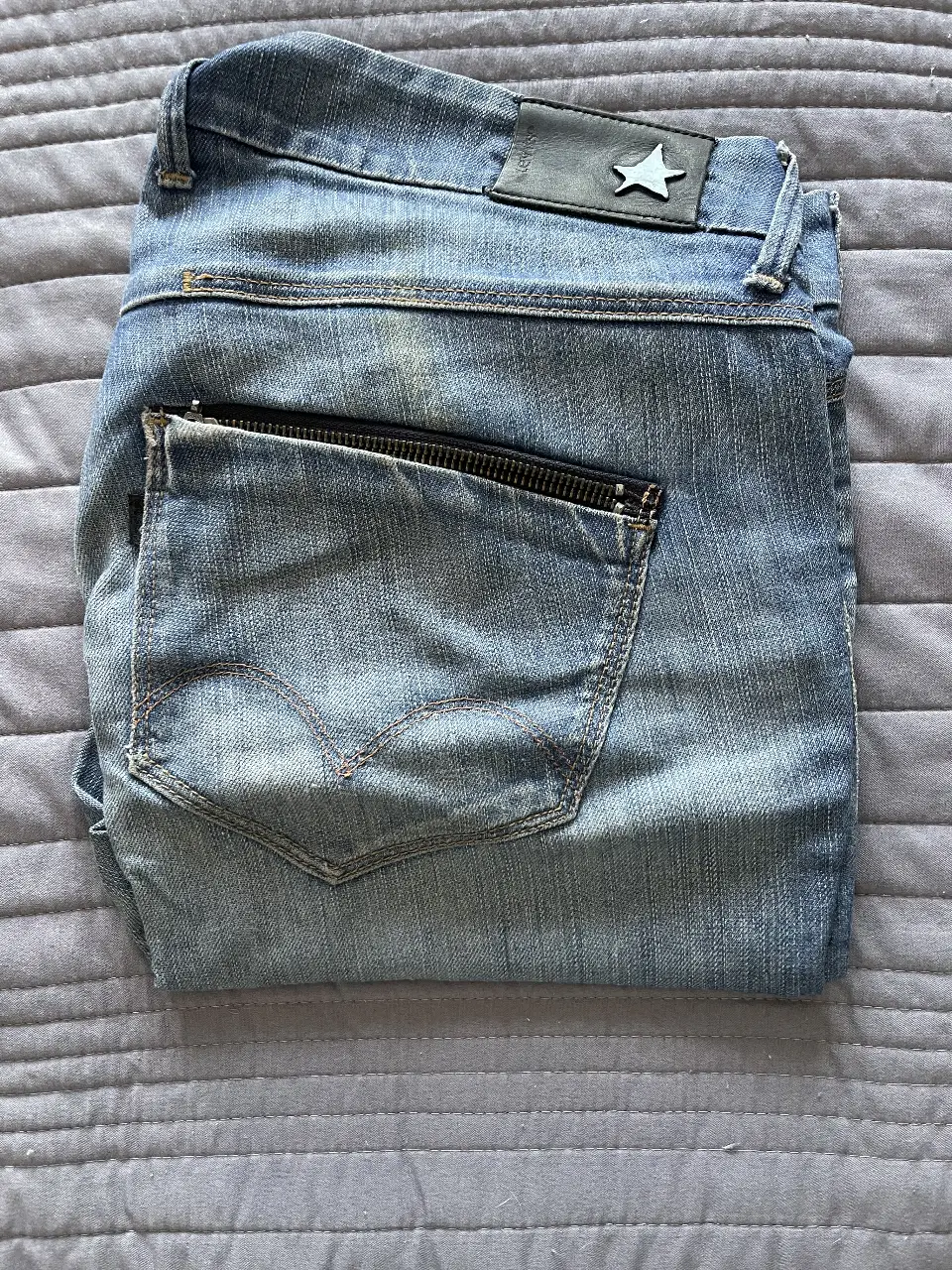 Jeans de hombre, corte recto, con detalles de cierre en los bolsillos traseros. Un clásico para cualquier ocasión.